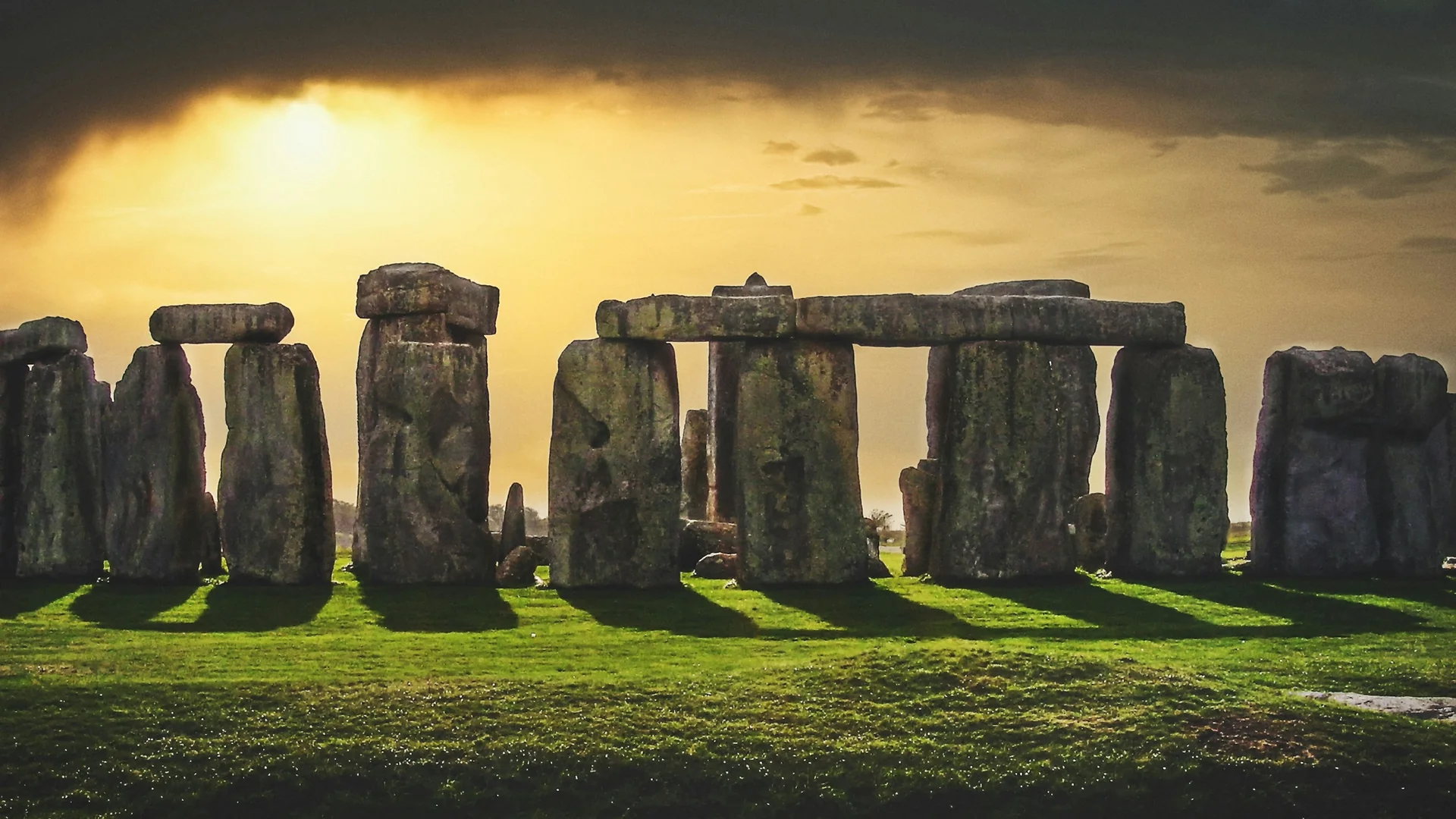 Stonehenge's sarsen stone circle silhouetted against an amber evening sky at sunset